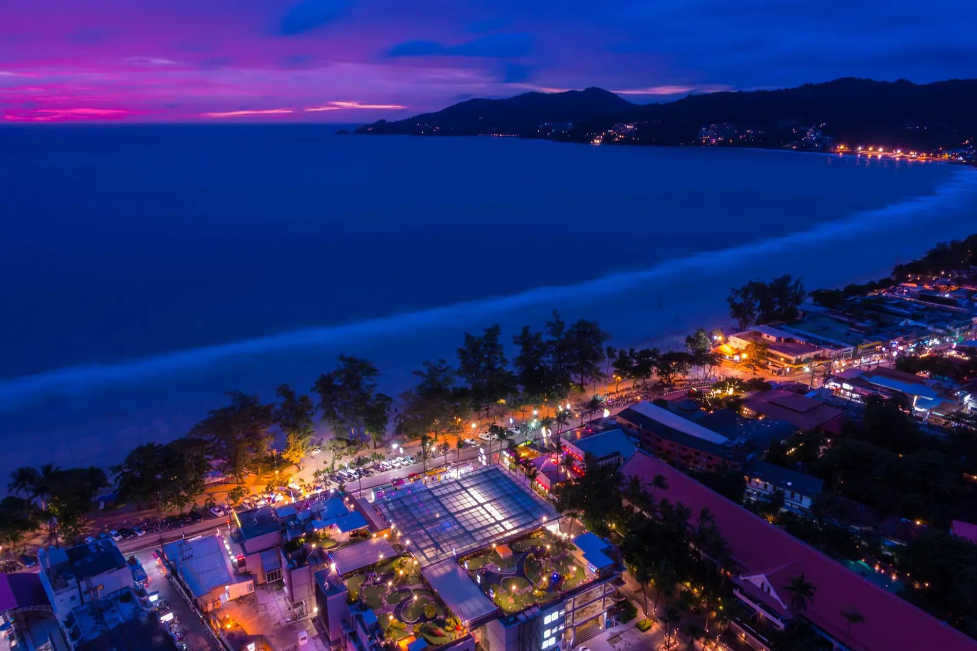 Aerial view of Patong Beach, Phuket at dusk with the coastline lit up