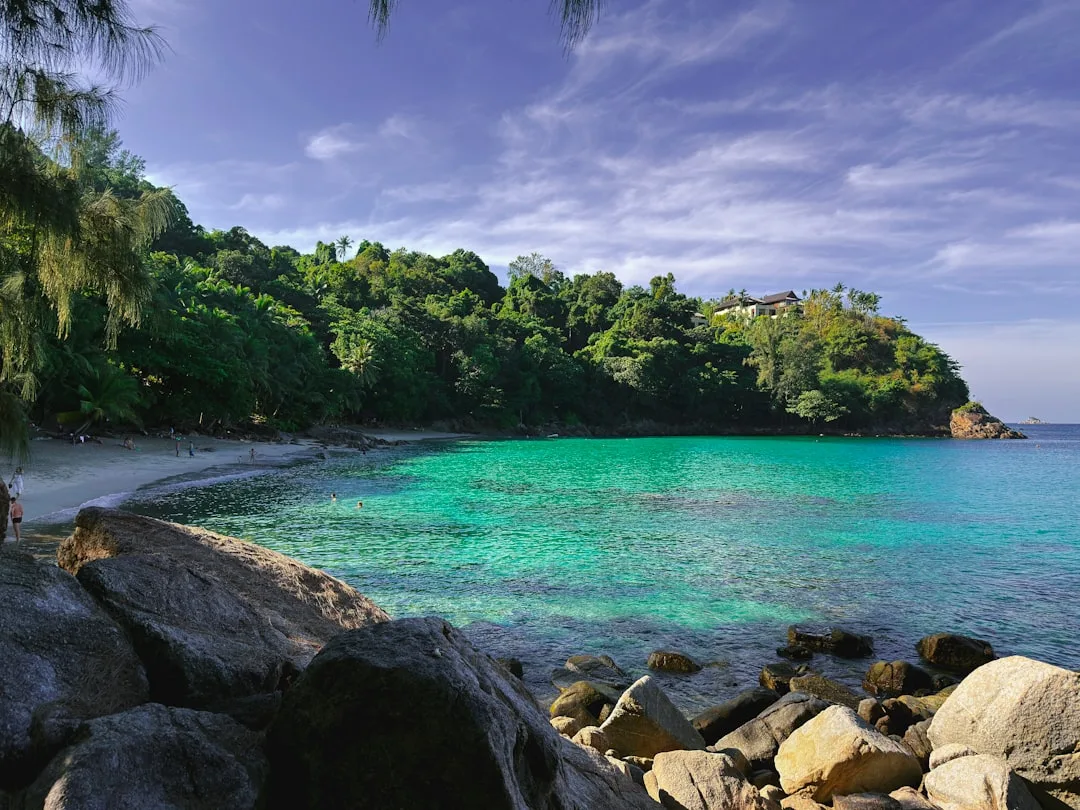 Quiet beaches Phuket — secluded cove with white sand, jungle backdrop, and clear Andaman Sea water