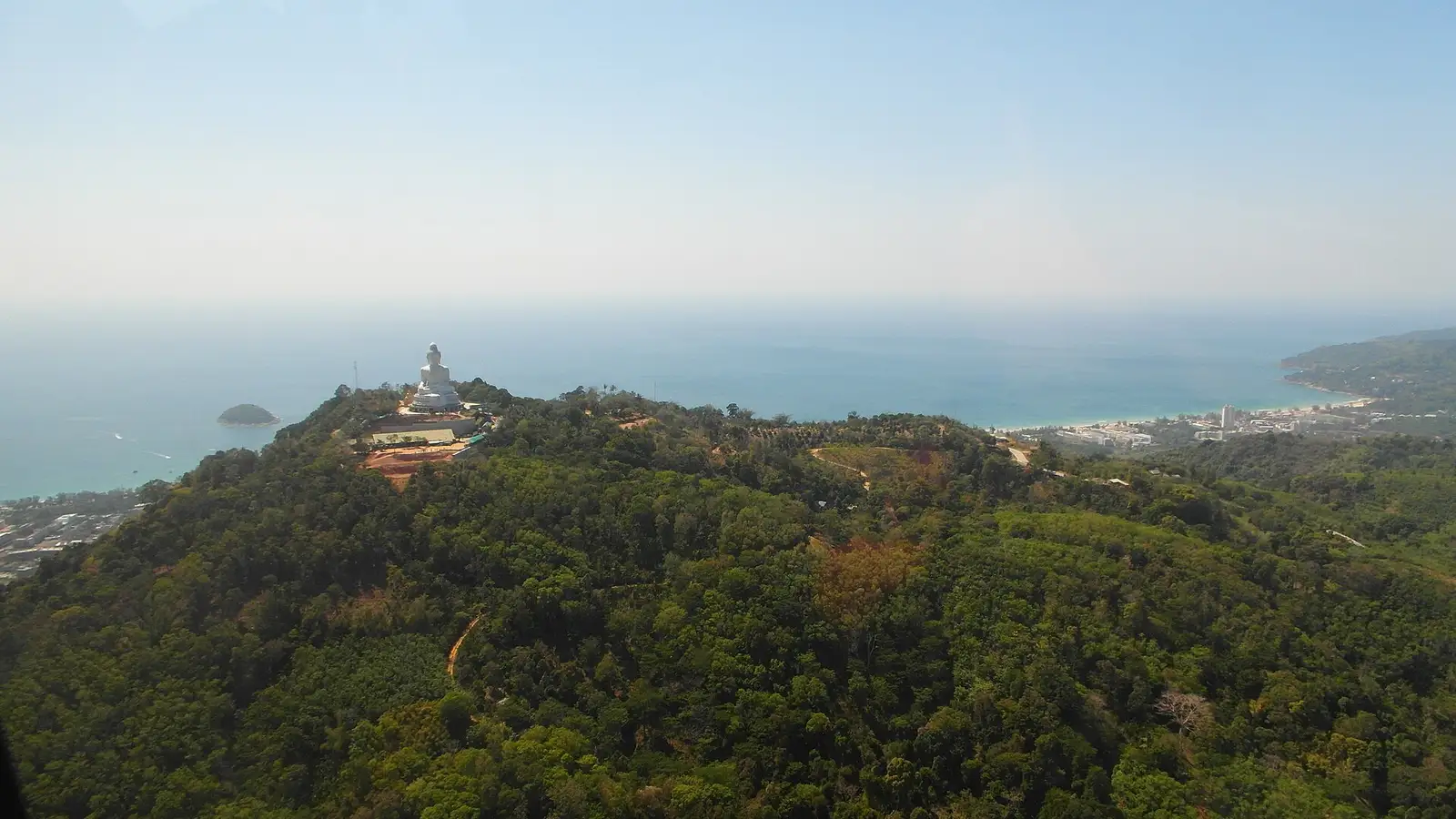 Aerial view of Nakkerd Hill with Big Buddha Phuket on the ridge, jungle slopes below and the west-coast beaches beyond
