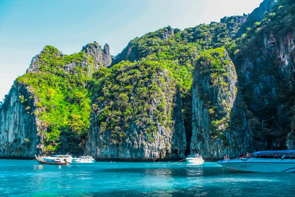 Longtail boats below limestone cliffs on a krabi day trip from phuket