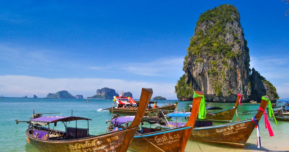 Panoramic view of Phuket coastline with longtail boats, green hills, and turquoise water