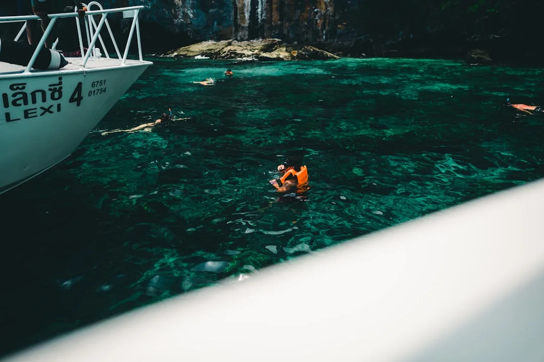 Snorkeler swimming over a shallow coral reef in clear turquoise water near Phuket, Thailand