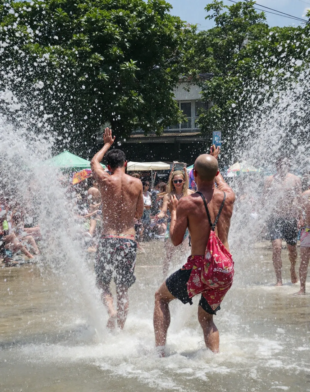 Friends splashing each other with water in a Phuket street fountain during Songkran