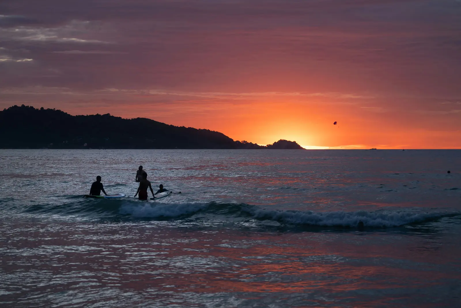 Surfer riding a wave while surfing Phuket at Kata Beach
